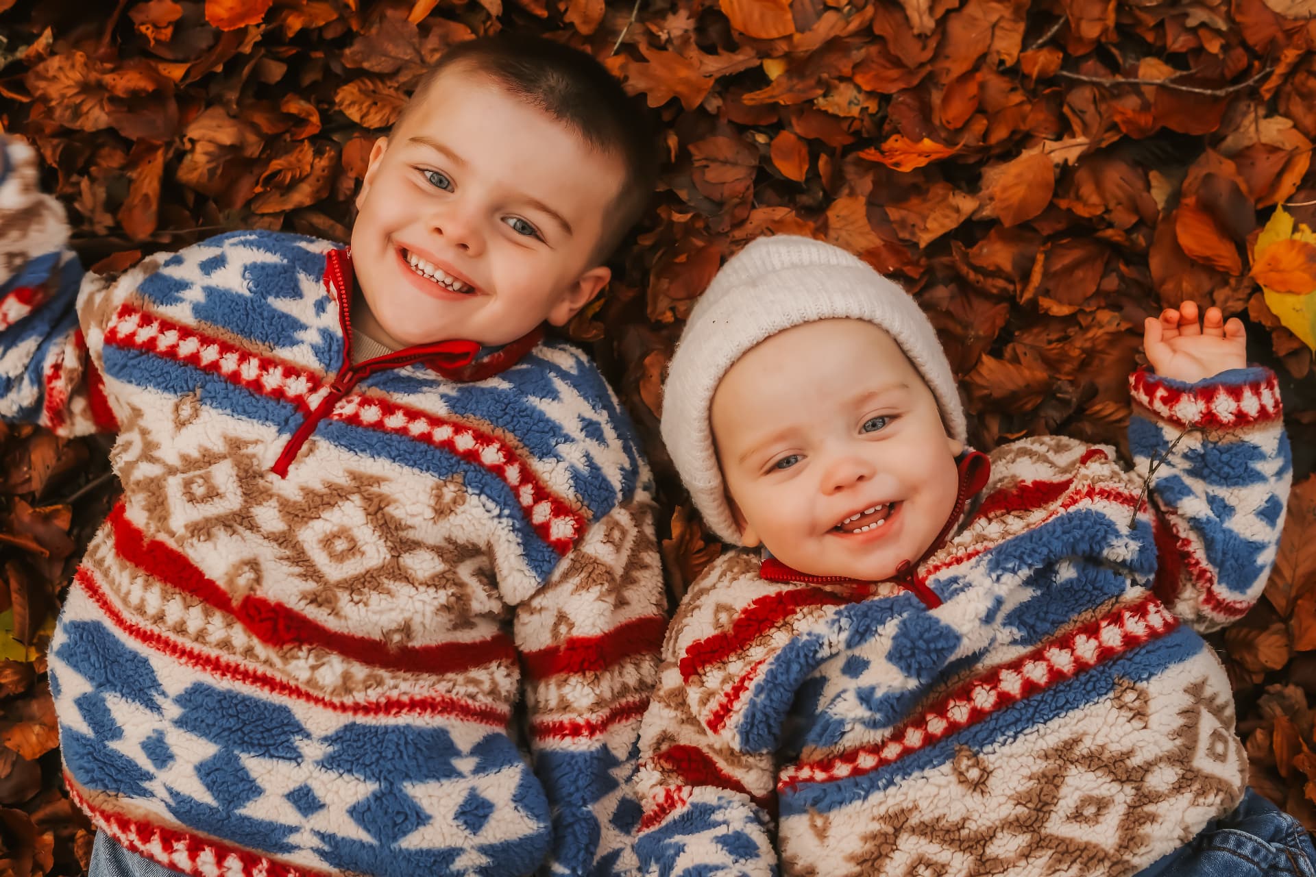 Two brothers lying in a bed of autumn leaves