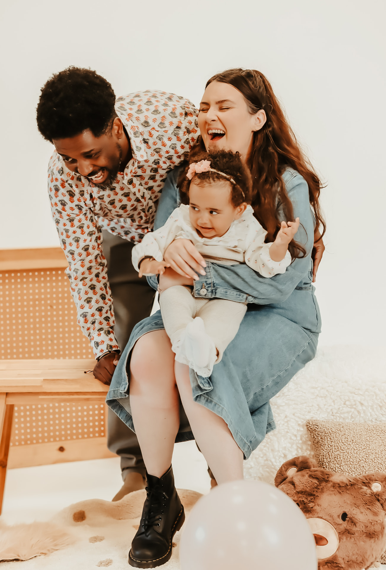 A young family laughing together in a bright studio portrait